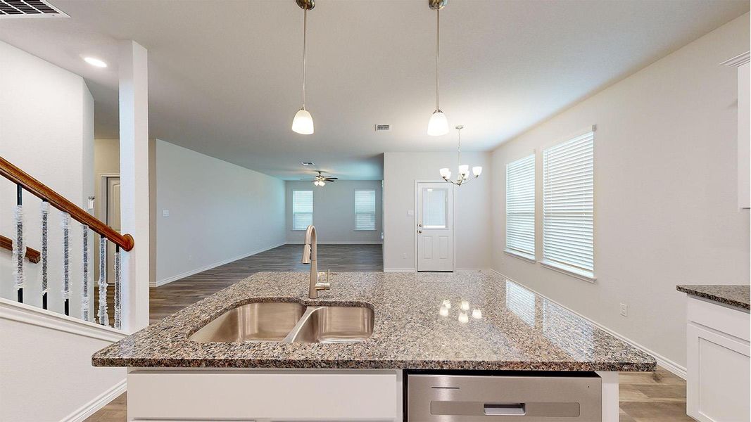 Kitchen island featuring a double-basin stainless steel sink, pull-down faucet, and granite countertop Kitchen island featuring a double-basin stainless steel sink, pull-down faucet, and granite countertop