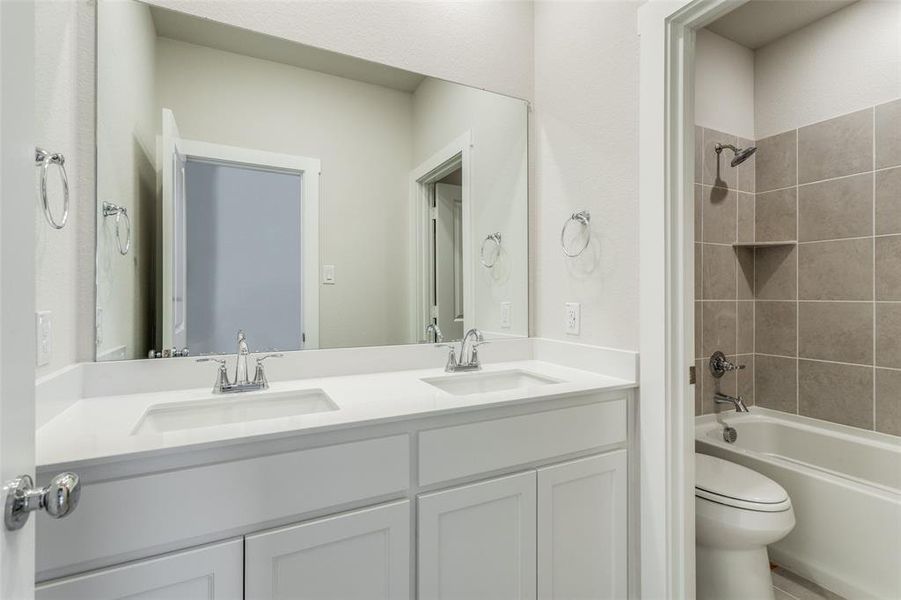 Full bathroom with tiled shower / bath, vanity, and toilet