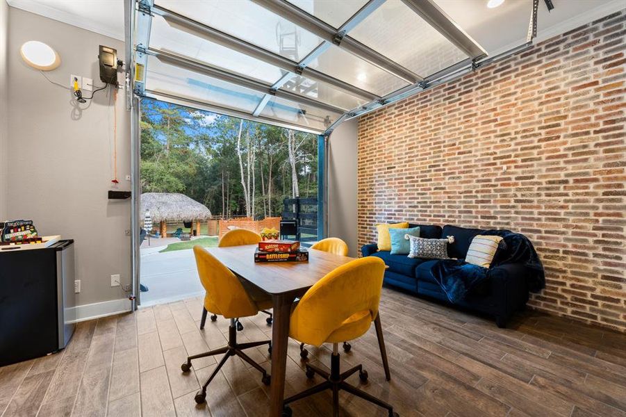 This unique room features a full sized glass garage door making it a true flex room.  It also features a full brick wall facing the dining room offering an extra design feature.