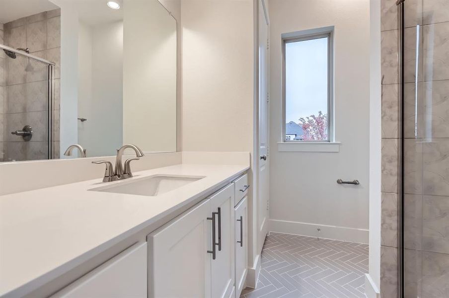 Bathroom featuring tile patterned floors, vanity, and a shower with shower door