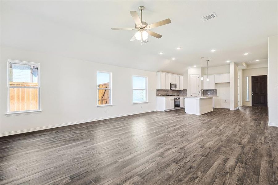 Unfurnished living room with plenty of natural light, ceiling fan, sink, and dark hardwood / wood-style flooring