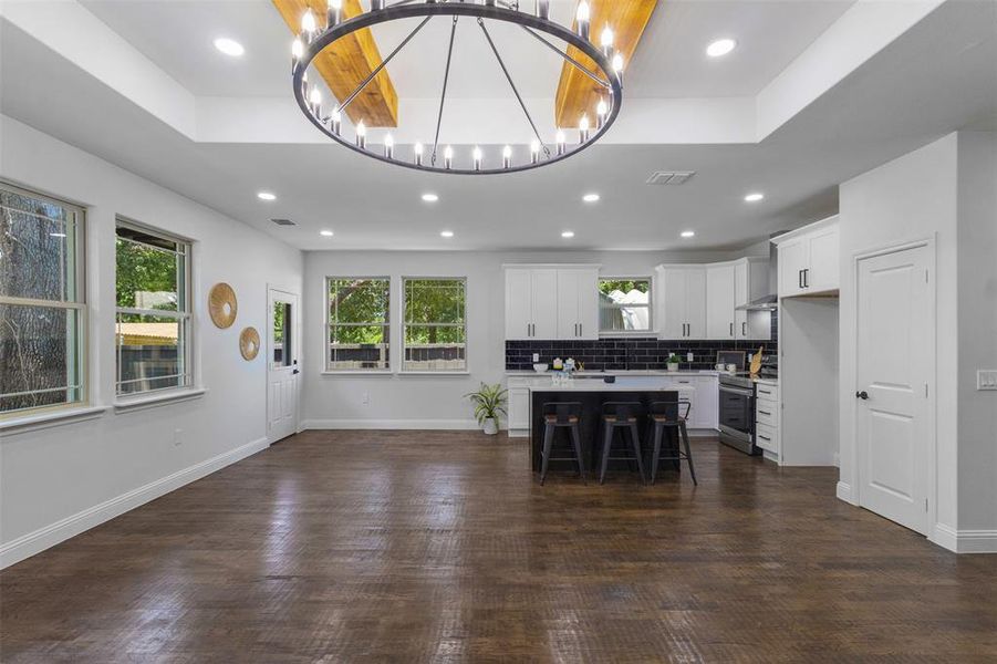 Kitchen with a chandelier, light countertops, a kitchen bar, a center island, and stainless steel electric range oven Kitchen with a chandelier, light countertops, a kitchen bar, a center island, and stainless steel electric range oven