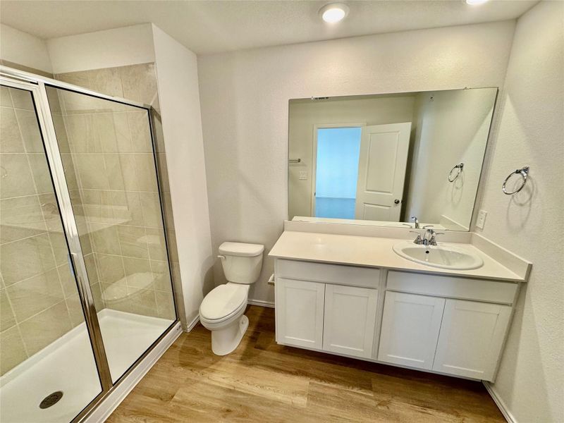 Bathroom featuring vanity, a stall shower, and light wood-style flooring