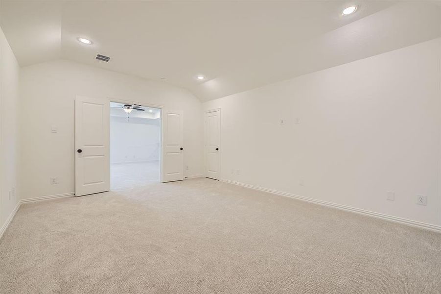 Carpeted empty room with ceiling fan and vaulted ceiling