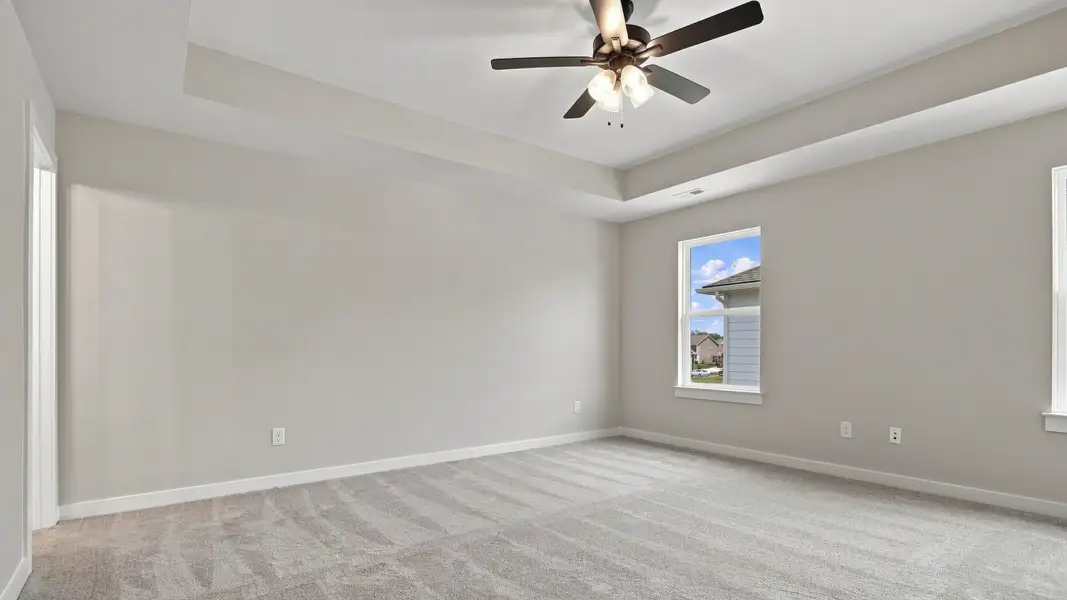 Angled shot of primary bedroom with window sights of community from upstairs