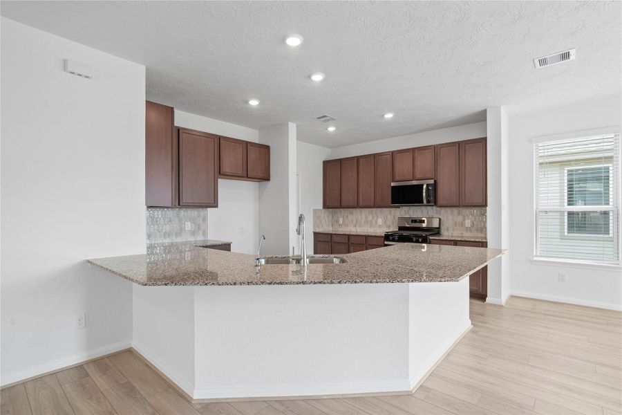 This stunning kitchen displays such a beautiful contrast with the ginger stained Woodmont cabinets, neutral paint, recessed lighting, granite countertops in Caramel Cream, Daltile Miramo Pearl backsplash, and SS appliances. The granite countertop also provides a spacious breakfast bar! This stunning kitchen displays such a beautiful contrast with the ginger stained Woodmont cabinets, neutral paint, recessed lighting, granite countertops in Caramel Cream, Daltile Miramo Pearl backsplash, and SS appliances. The granite countertop also provides a spacious breakfast bar!
