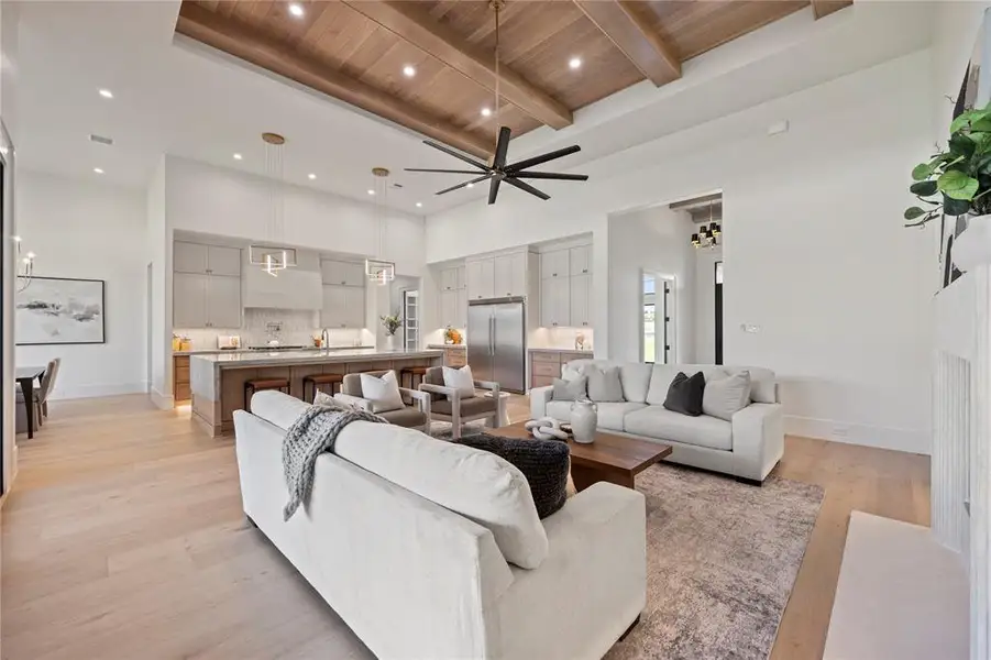 Living area with a ceiling fan, a wooden ceiling with exposed beams, light wood finished floors, recessed lighting, and a towering ceiling
