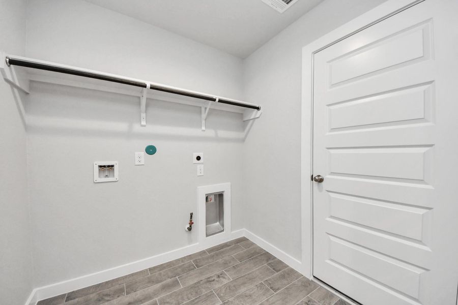 A perfect blend of functionality and comfort. Capture the essence of easy living with a first-floor laundry room, thoughtfully equipped with shelving for effortless organization. Both electric and gas connections available. Sample photo of completed home with similar floor plan. Actual colors and selections may vary. A perfect blend of functionality and comfort. Capture the essence of easy living with a first-floor laundry room, thoughtfully equipped with shelving for effortless organization. Both electric and gas connections available. Sample photo of completed home with similar floor plan. Actual colors and selections may vary.