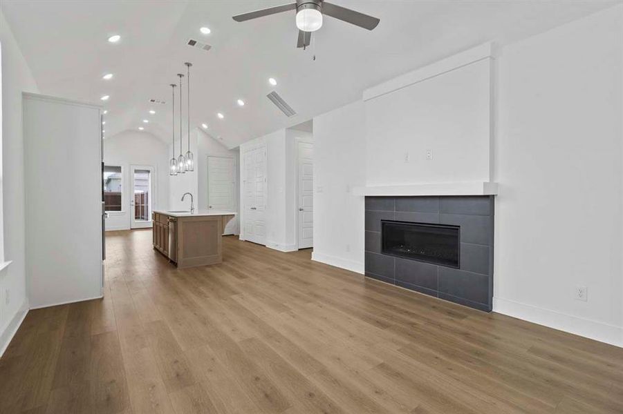 Unfurnished living room with vaulted ceiling, dark wood-style flooring, a tiled fireplace, recessed lighting, and ceiling fan Unfurnished living room with vaulted ceiling, dark wood-style flooring, a tiled fireplace, recessed lighting, and ceiling fan
