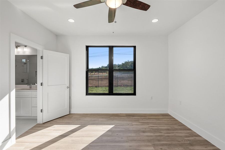 Unfurnished bedroom featuring light wood-style flooring, recessed lighting, a ceiling fan, and ensuite bath