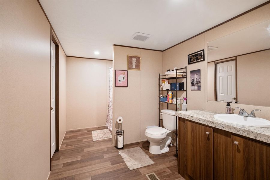 Full bath with dark wood finished floors, vanity, a shower with curtain, recessed lighting, and crown molding