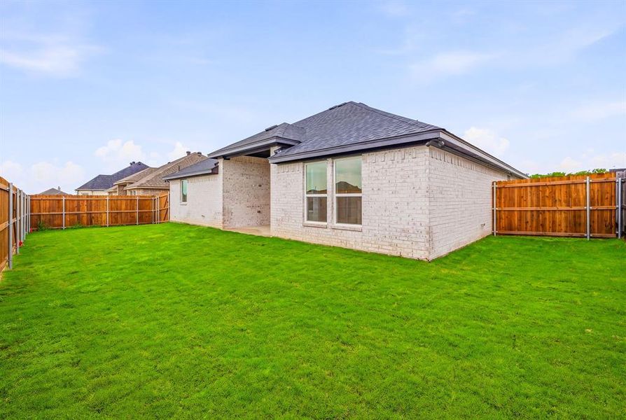 The property features a well-maintained lawn and a privacy fence