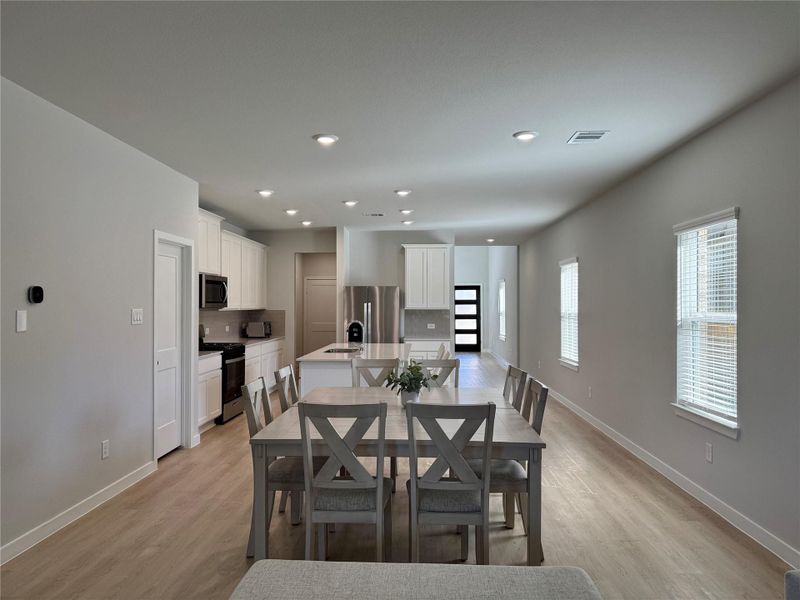 Modern open-concept kitchen and dining area. It features light wood flooring, white cabinetry, and stainless steel appliances. The space is bright with natural light from multiple windows, offering a welcoming atmosphere. Modern open-concept kitchen and dining area. It features light wood flooring, white cabinetry, and stainless steel appliances. The space is bright with natural light from multiple windows, offering a welcoming atmosphere.