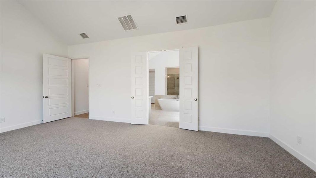 Unfurnished bedroom with light carpet and vaulted ceiling