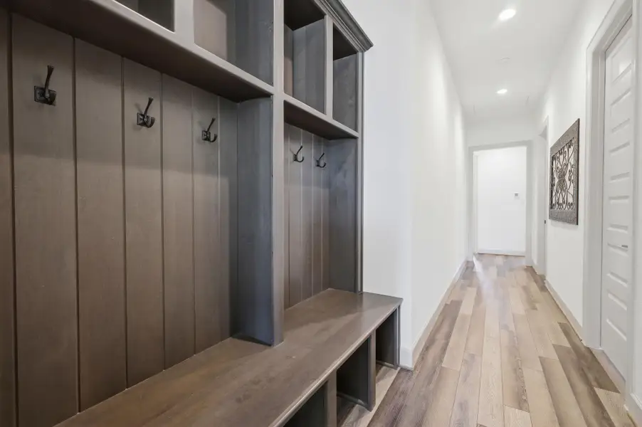 Hallway with hardwood floors, recessed lighting, and a built-in storage unit featuring a bench and coat hooks