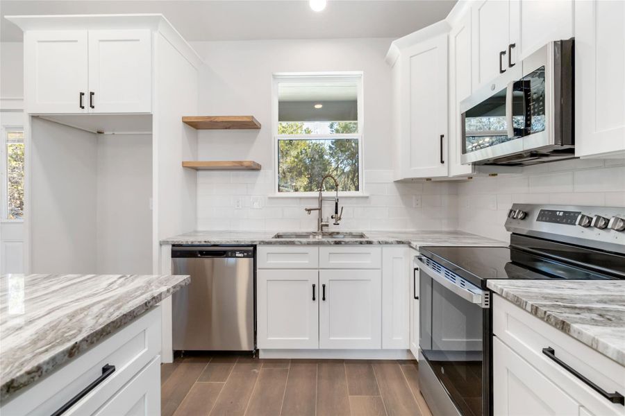 Kitchen with white cabinetry, appliances with stainless steel finishes, and sink