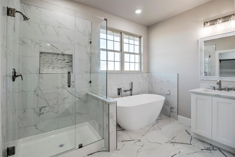 Bathroom featuring a freestanding bath, light marble finish flooring, vanity, a marble finish shower, and recessed lighting
