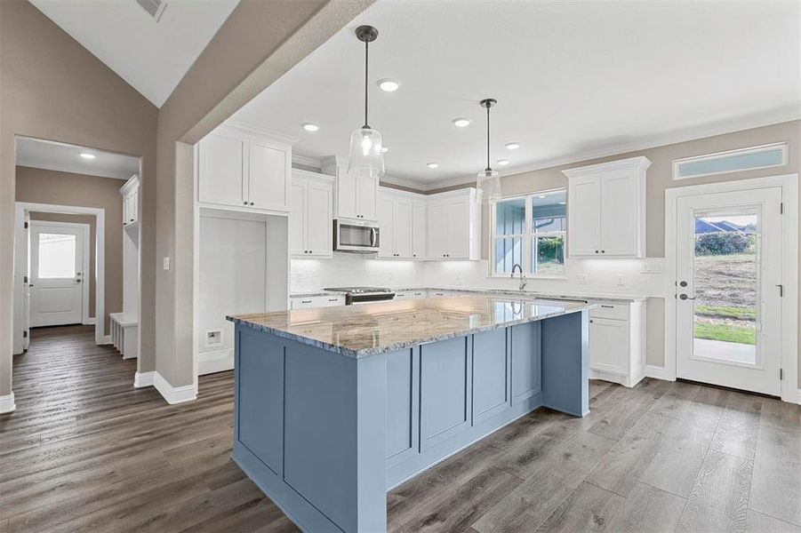 Kitchen featuring pendant lighting, white cabinets, a center island, and stainless steel appliances