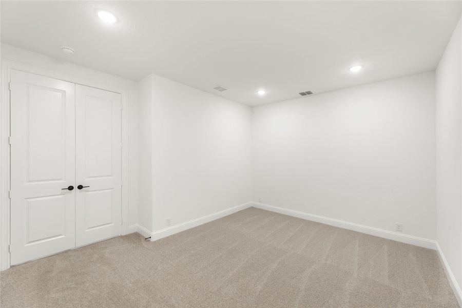 Empty room with beige carpet, white walls, recessed lighting, and double white doors with black handles Empty room with beige carpet, white walls, recessed lighting, and double white doors with black handles