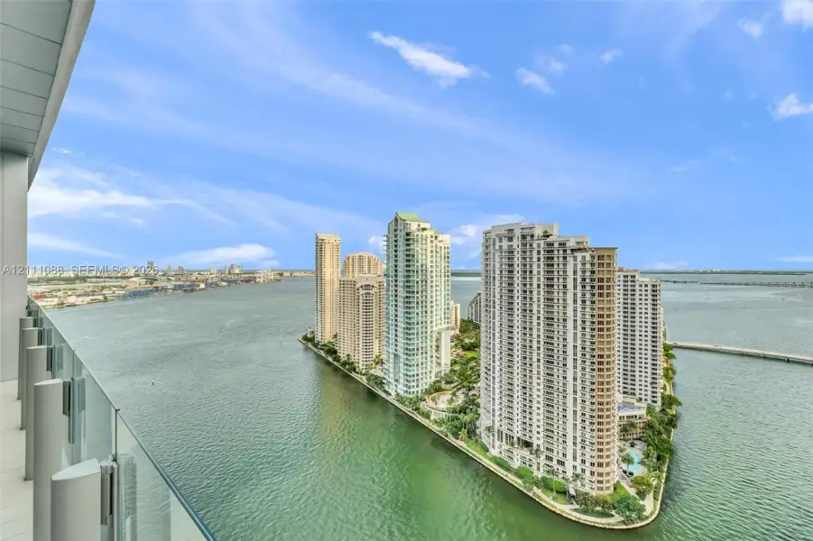 Covered balcony featuring a glass panel railing and panoramic water-facing exposure Covered balcony featuring a glass panel railing and panoramic water-facing exposure