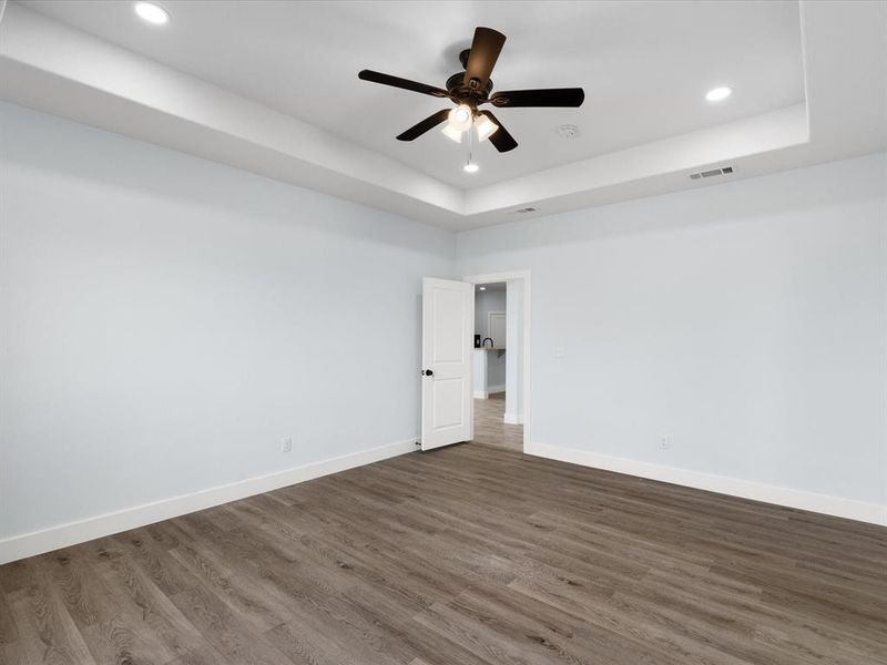 Unfurnished room featuring recessed lighting, a raised ceiling, dark wood-type flooring, and a ceiling fan
