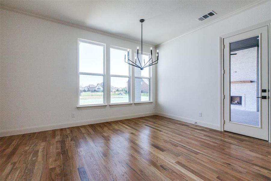 Empty room with wood-type flooring, an inviting chandelier, and plenty of natural light