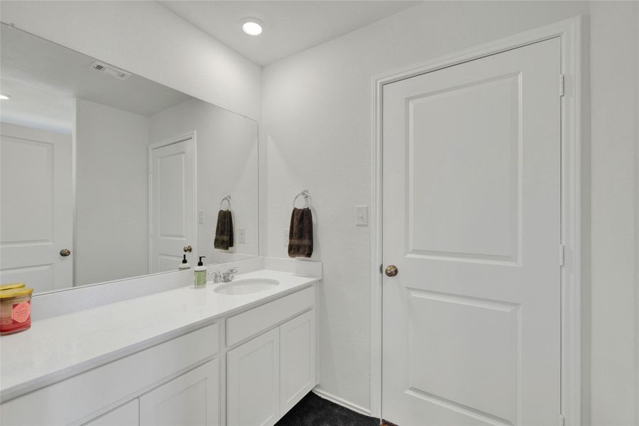 White countertops and cabinetry define this contemporary primary bathroom.