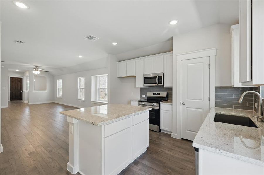 Kitchen with appliances with stainless steel finishes, tasteful backsplash, white cabinetry, and recessed lighting Kitchen with appliances with stainless steel finishes, tasteful backsplash, white cabinetry, and recessed lighting