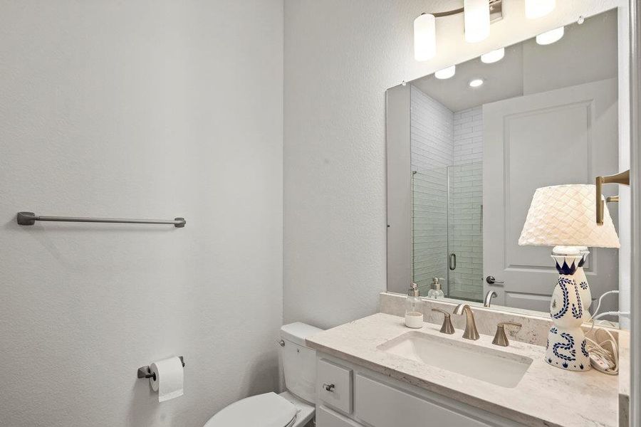 Full bathroom featuring vanity, toilet, and a shower stall