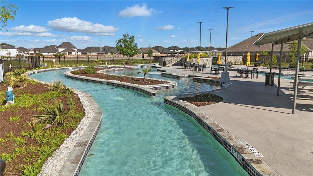 Resort-style pool area featuring a winding lazy river, integrated seating areas, surrounding landscaping, and a shaded pergola Resort-style pool area featuring a winding lazy river, integrated seating areas, surrounding landscaping, and a shaded pergola
