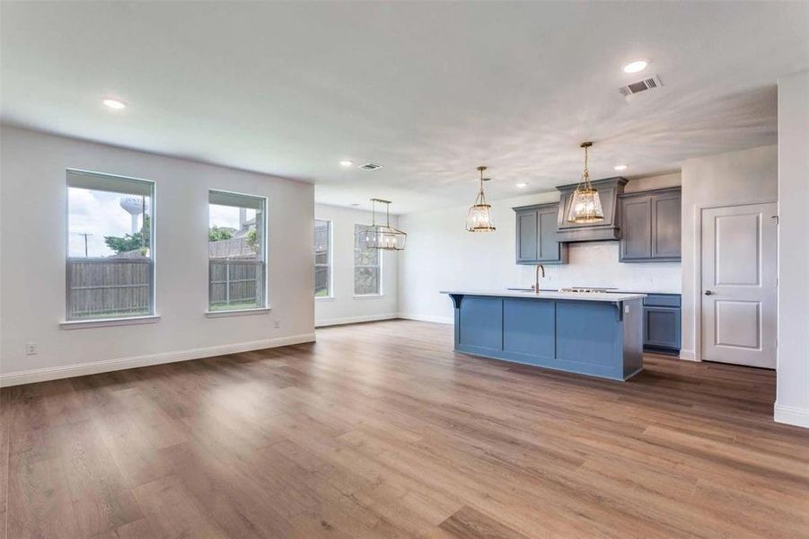Kitchen featuring custom range hood, recessed lighting, wood finished floors, pendant lighting, and open floor plan Kitchen featuring custom range hood, recessed lighting, wood finished floors, pendant lighting, and open floor plan