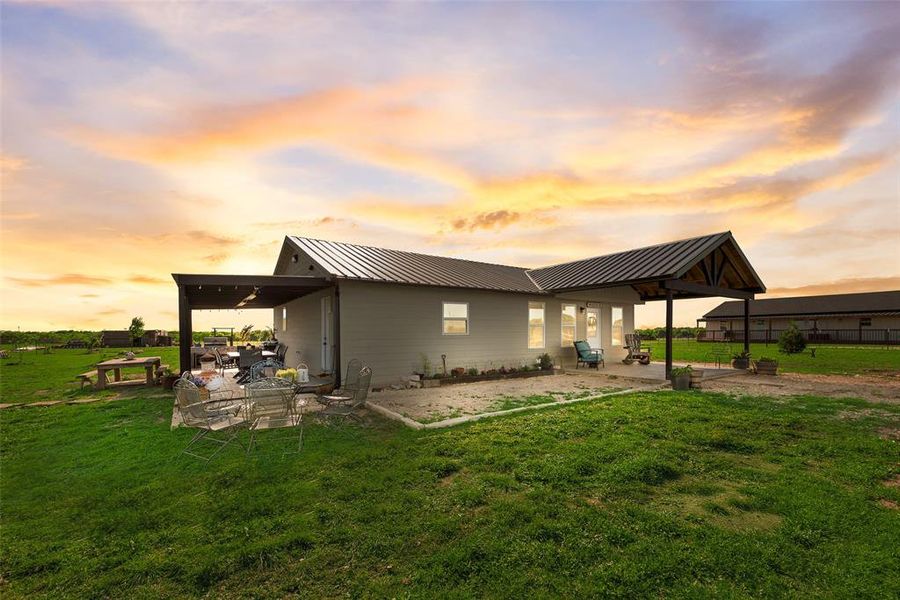 Back of house at dusk with a gazebo, a patio area, metal roof, and a lawn