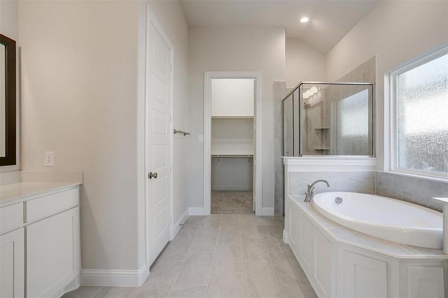 Bathroom with tile patterned flooring, vanity, lofted ceiling, and shower with separate bathtub