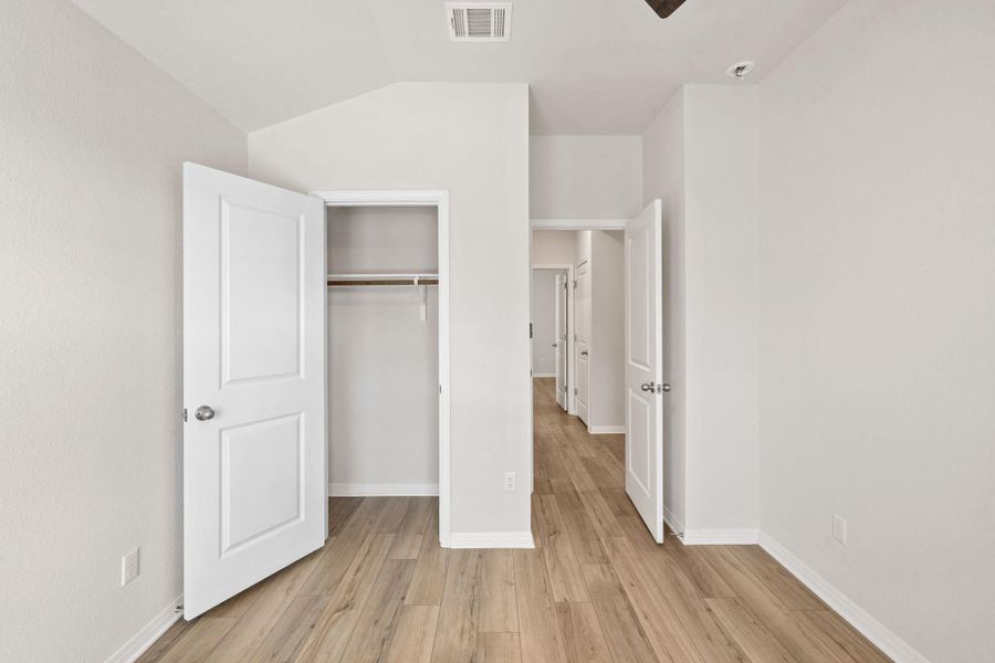 Unfurnished bedroom featuring light wood finished floors, a closet, and lofted ceiling Unfurnished bedroom featuring light wood finished floors, a closet, and lofted ceiling