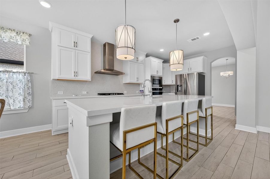 Clean lines, soft tones, and a striking range hood create a contemporary culinary space. The large island comfortably seats four and anchors the open layout.