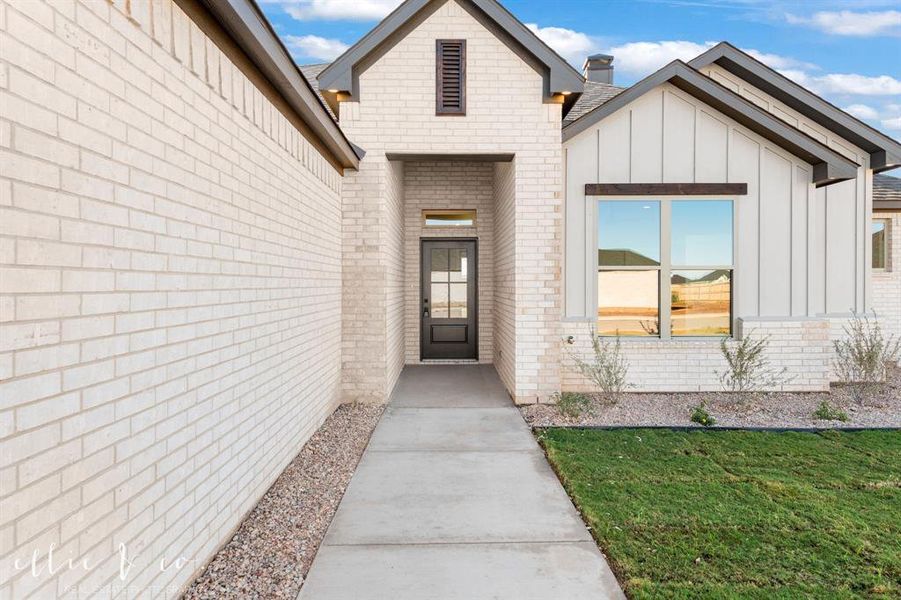 Property entrance with board and batten siding and brick siding