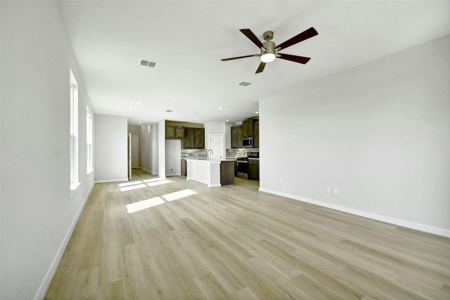 Unfurnished living room featuring ceiling fan, light hardwood / wood-style flooring, and sink