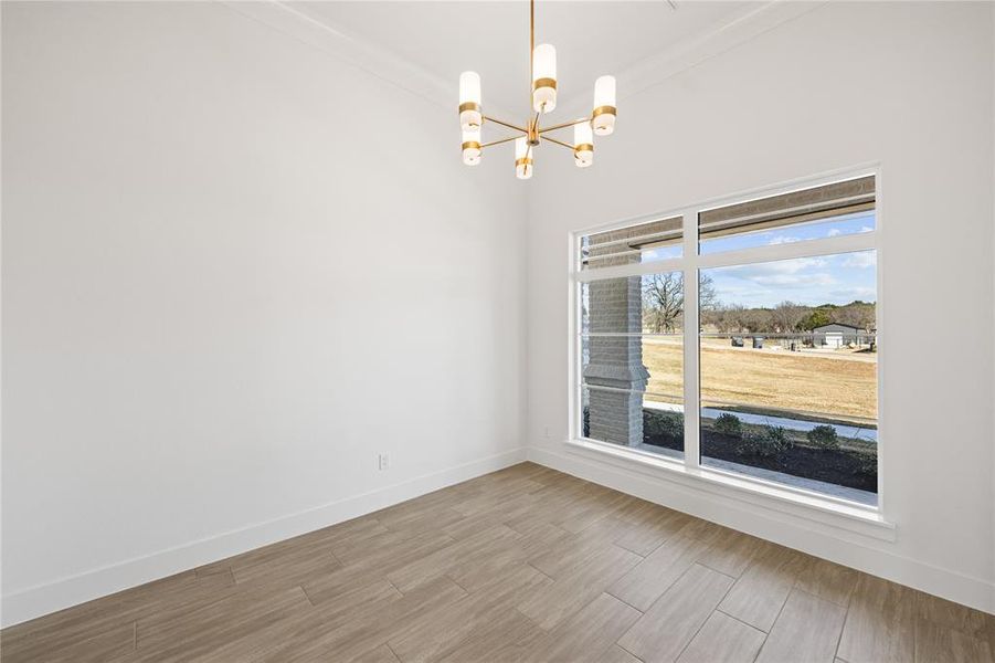 Spare room with suspended lighting, crown molding, and wood finish floors