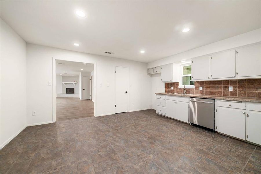 Kitchen featuring tasteful backsplash, white cabinets, a sink, and stainless steel dishwasher Kitchen featuring tasteful backsplash, white cabinets, a sink, and stainless steel dishwasher