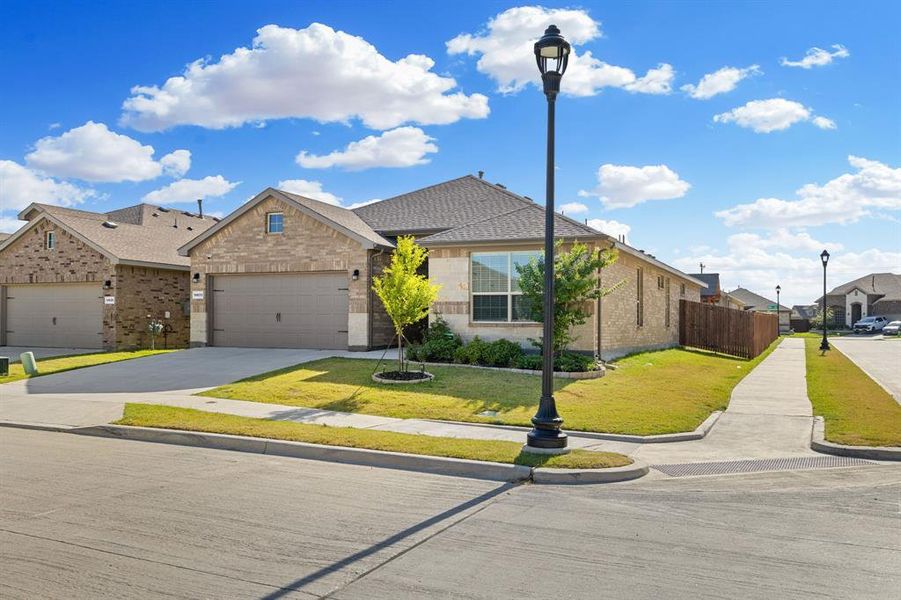 View of front facade with an attached garage, concrete driveway, a residential view, brick siding, and a shingled roof