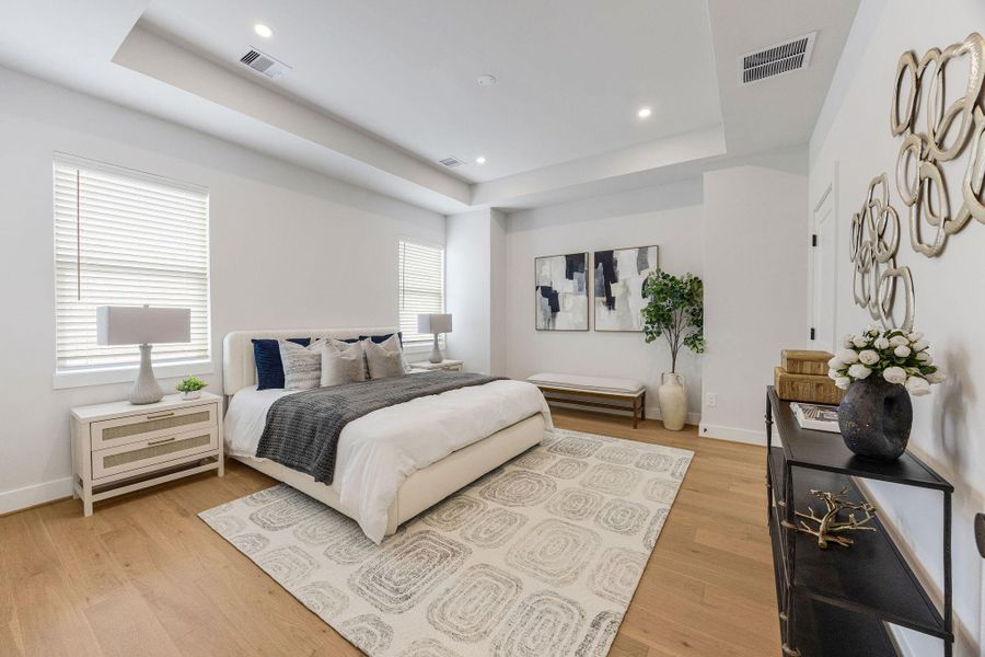 Spacious primary suite featuring tray ceilings, oversized windows, hardwood flooring, and designer finishes creating a peaceful retreat in one of Houston’s fastest-growing neighborhoods.