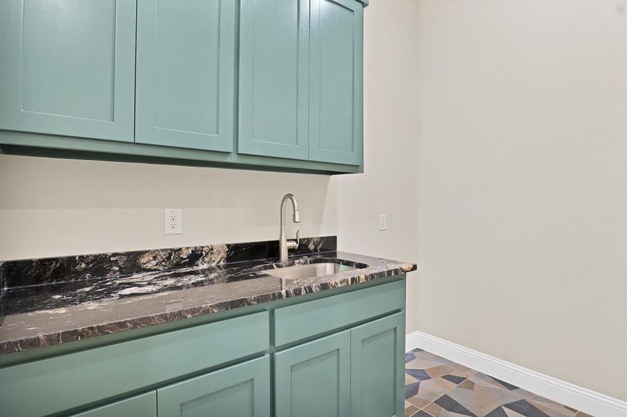 Kitchen featuring dark stone countertops, green cabinets, and sink