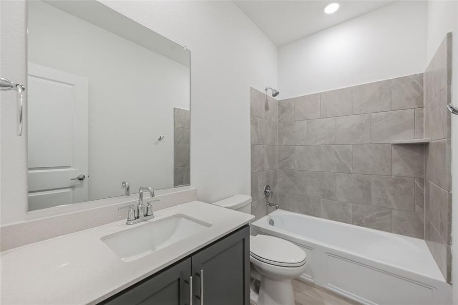 Full bathroom with toilet, tiled shower / bath combo, and vanity