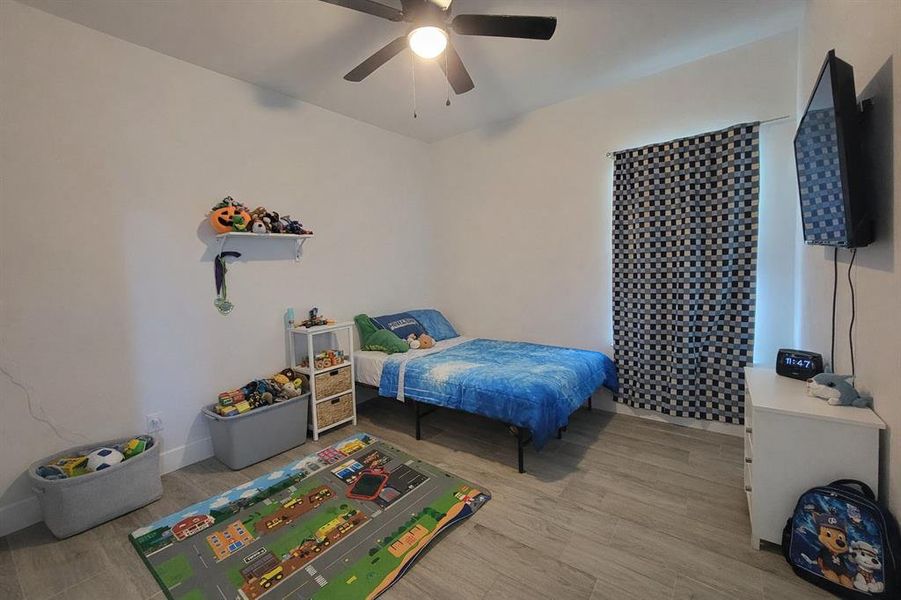 Bedroom featuring light wood-type flooring and ceiling fan Bedroom featuring light wood-type flooring and ceiling fan