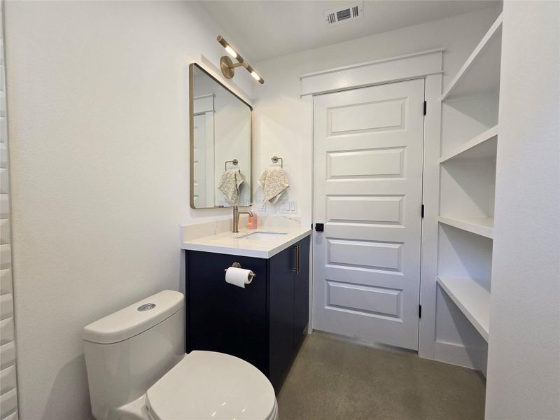 Secondary bathroom with matching cabinetry and Silestone counter top, and out of view shelving storage behind the door. Secondary bathroom with matching cabinetry and Silestone counter top, and out of view shelving storage behind the door.