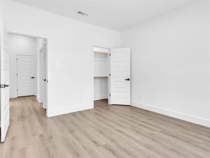 Unfurnished bedroom with a closet, visible vents, light wood finished floors, and baseboards Unfurnished bedroom with a closet, visible vents, light wood finished floors, and baseboards
