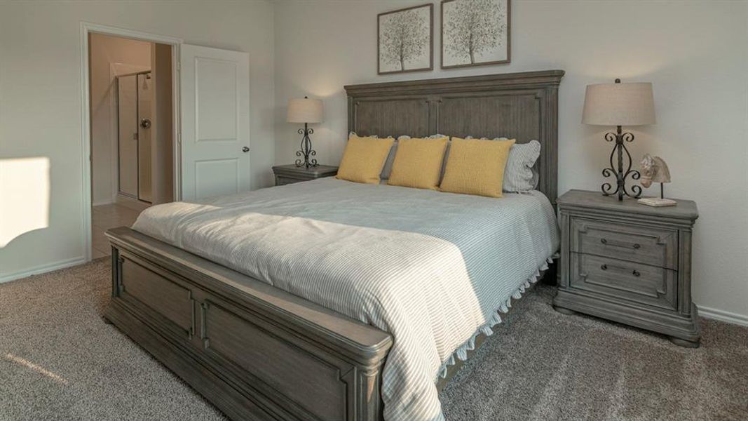 Carpeted bedroom featuring a neutral color palette, a solid door, and an entryway to an adjoining bathroom with a glass-enclosed shower