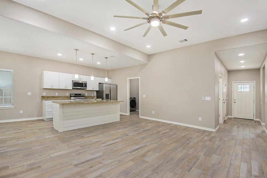 Kitchen with an island with sink, light wood-style floors, recessed lighting, stainless steel appliances, and ceiling fan