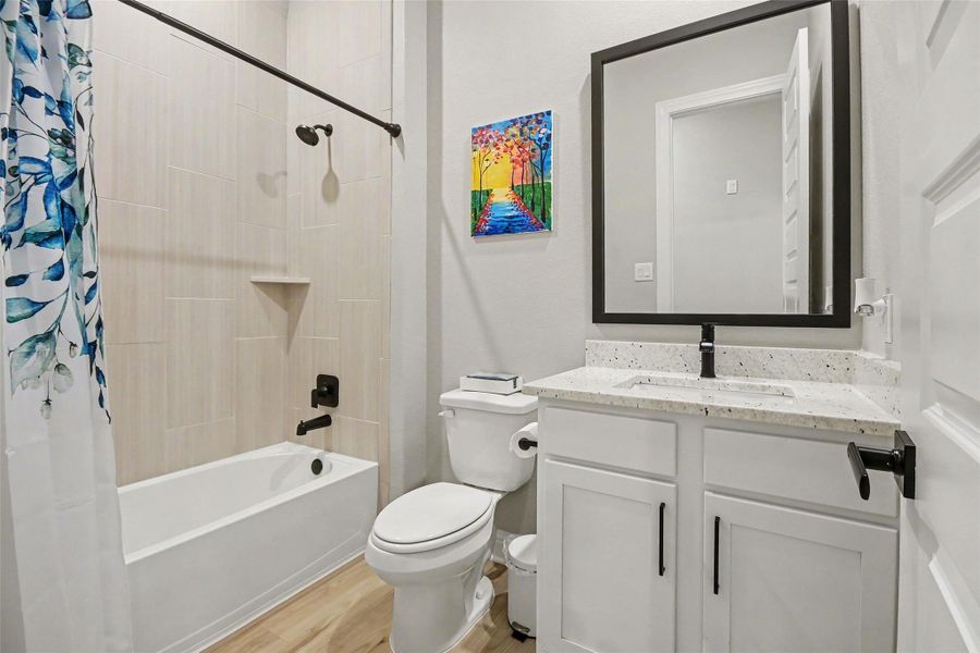 This modern bathroom features a sleek design with a bathtub and shower combo, a stylish vanity with a granite countertop, and a large framed mirror. The space is accented with a colorful wall art piece and a vibrant shower curtain, adding a touch of personality. This modern bathroom features a sleek design with a bathtub and shower combo, a stylish vanity with a granite countertop, and a large framed mirror. The space is accented with a colorful wall art piece and a vibrant shower curtain, adding a touch of personality.