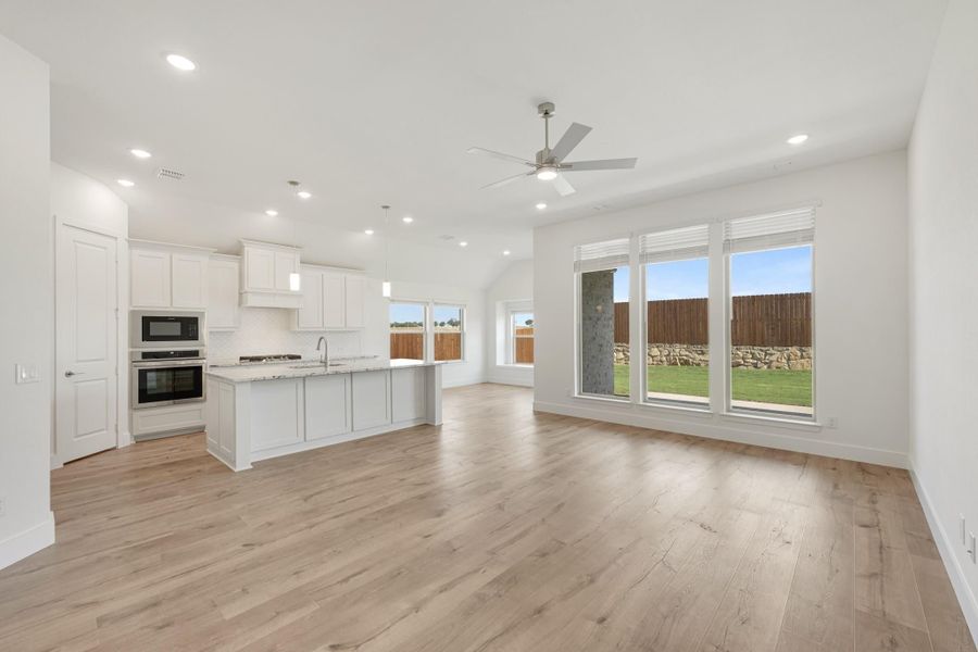 Open-concept living area and kitchen with white cabinets, center island, hardwood floors, and ceiling fan Open-concept living area and kitchen with white cabinets, center island, hardwood floors, and ceiling fan